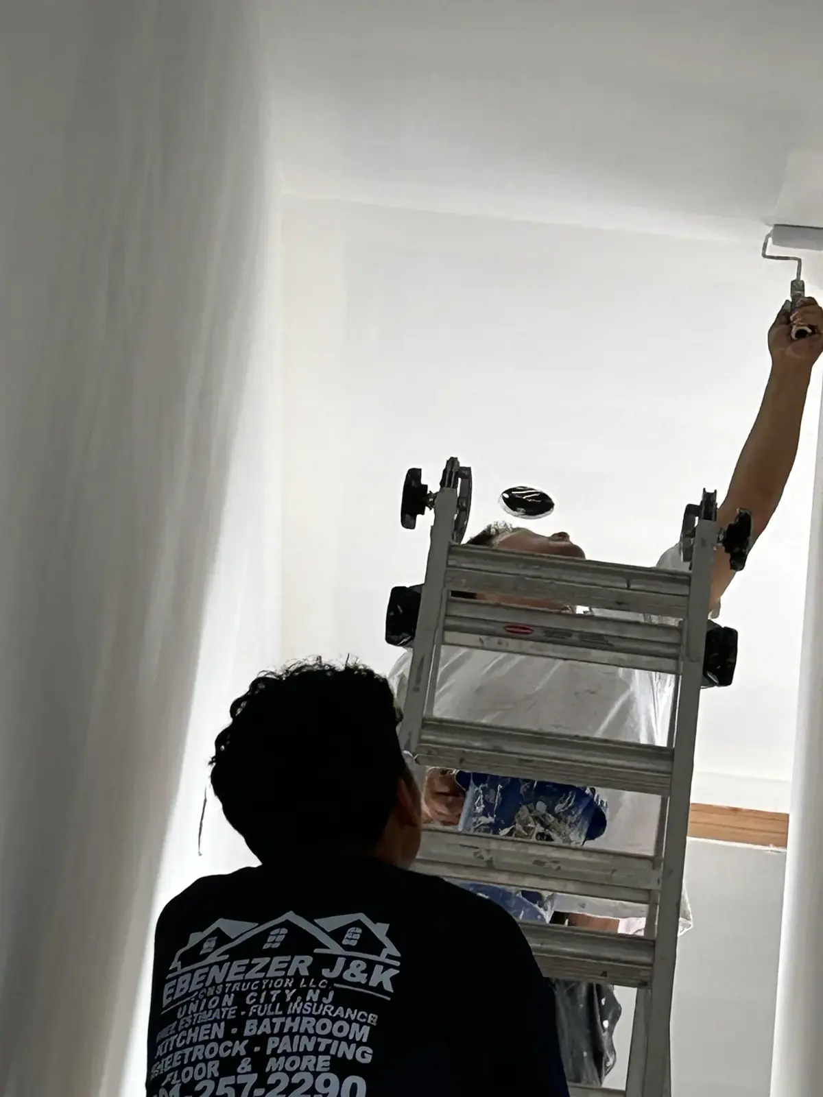 Worker finishing or painting a wall from a ladder